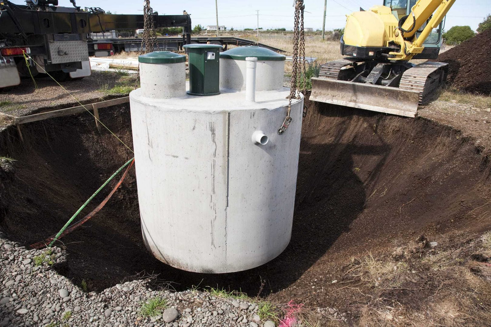 A large septic tank in the ground next to a bulldozer at Toronto Campground.