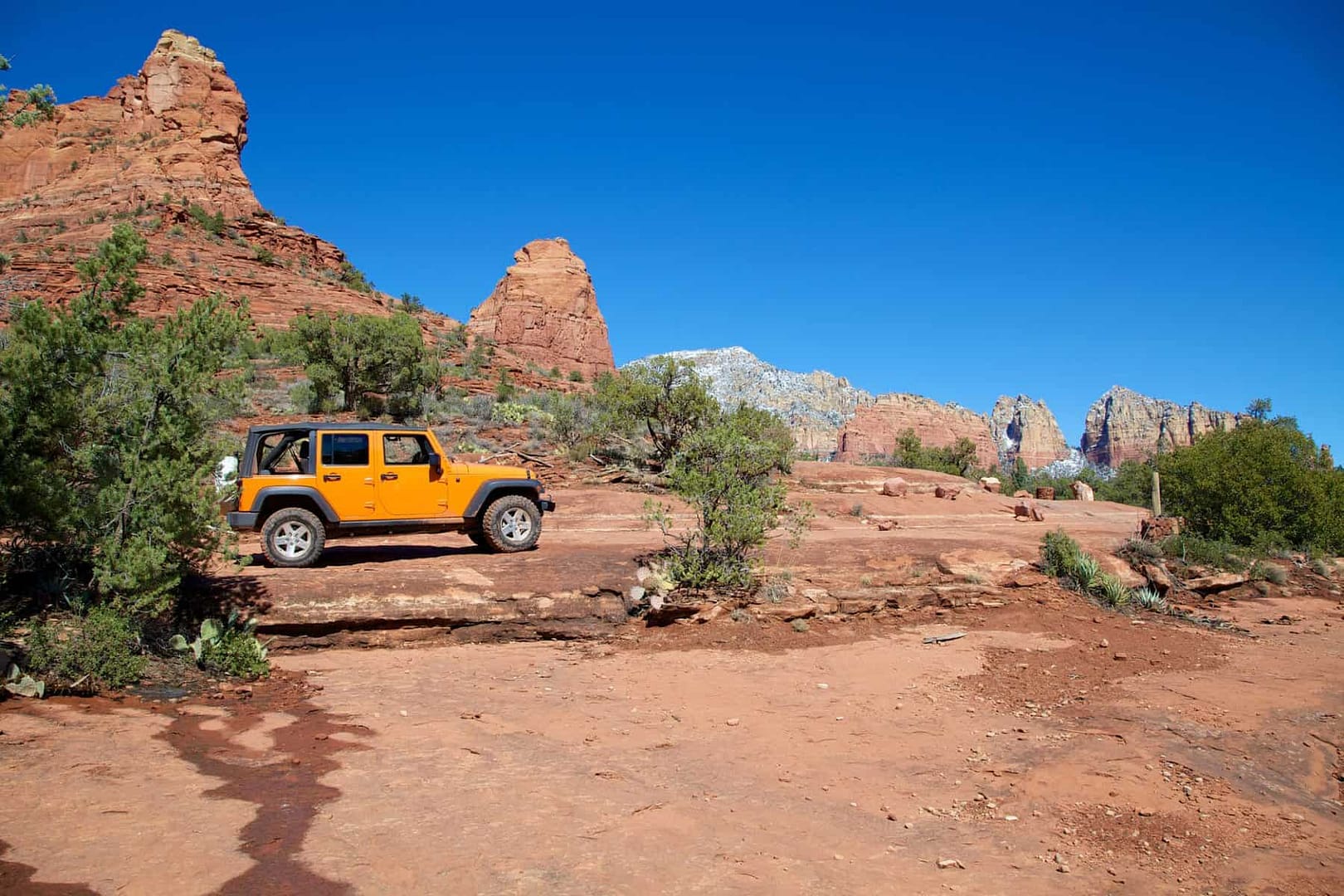 A 4WD-accessible orange jeep is parked on a rocky trail in Sedona.