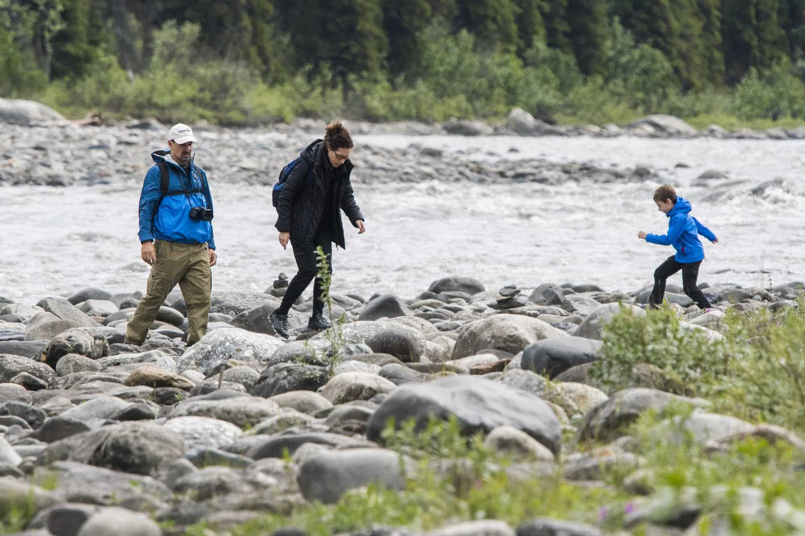 A virtual public meeting discussing trail development near a river, showcasing a group of people walking on rocks.