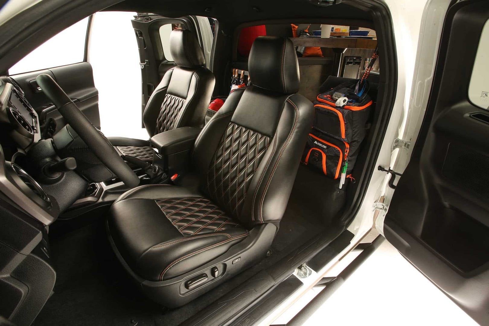The interior of a car transformed into a home-on-wheels, featuring sleek black leather seats.