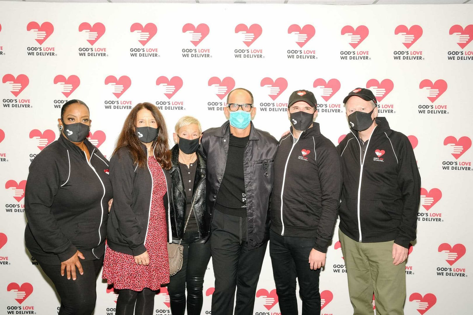 A group of people wearing face masks posing for a $1.5 Million Surprise Visit photo.