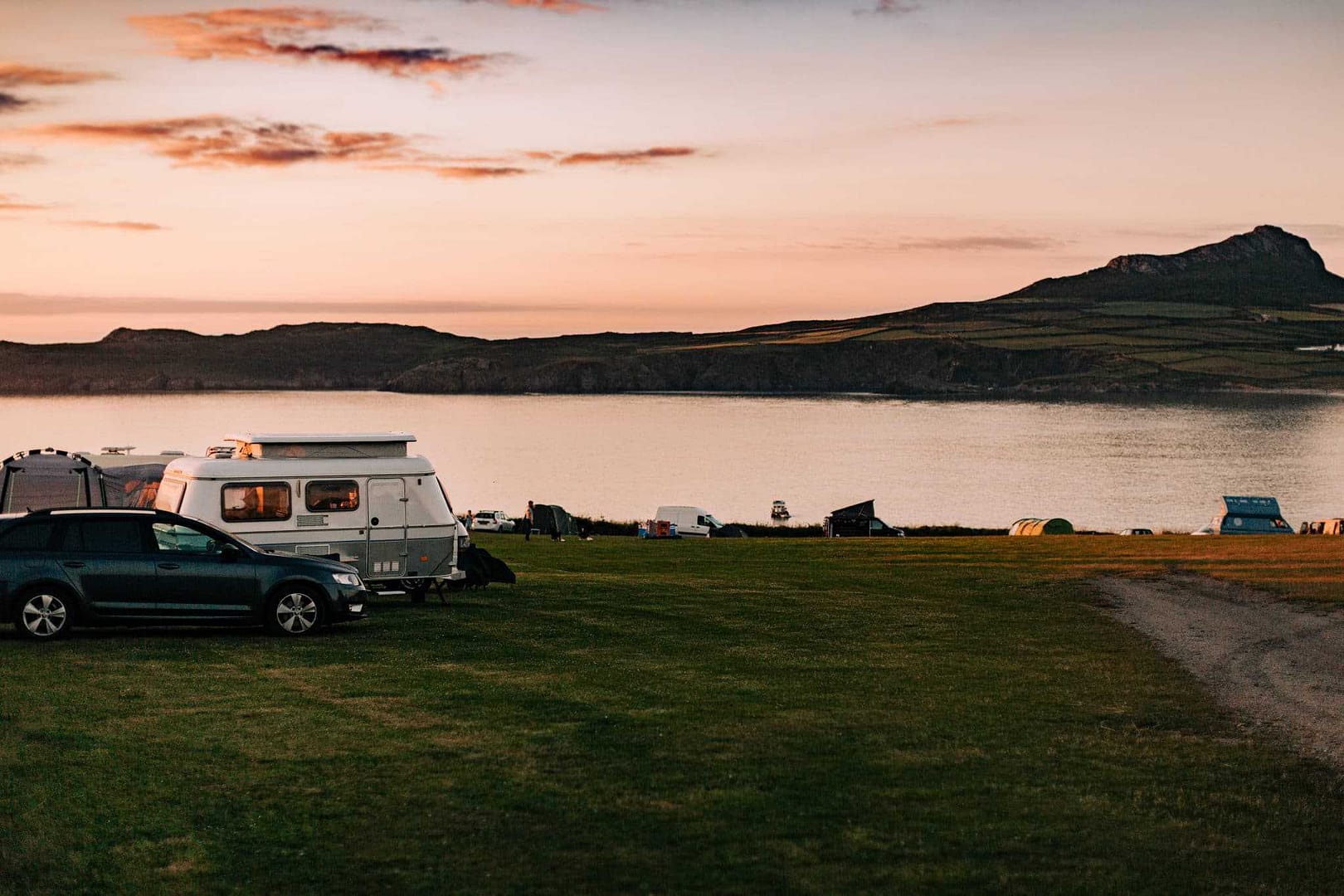 An RV parked on a grassy field overlooking the sea.