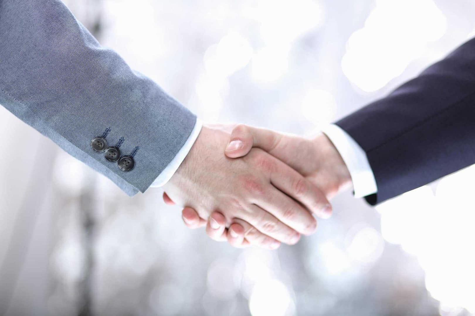 Two businessmen shaking hands in front of a blurred background at Summerhill Resorts