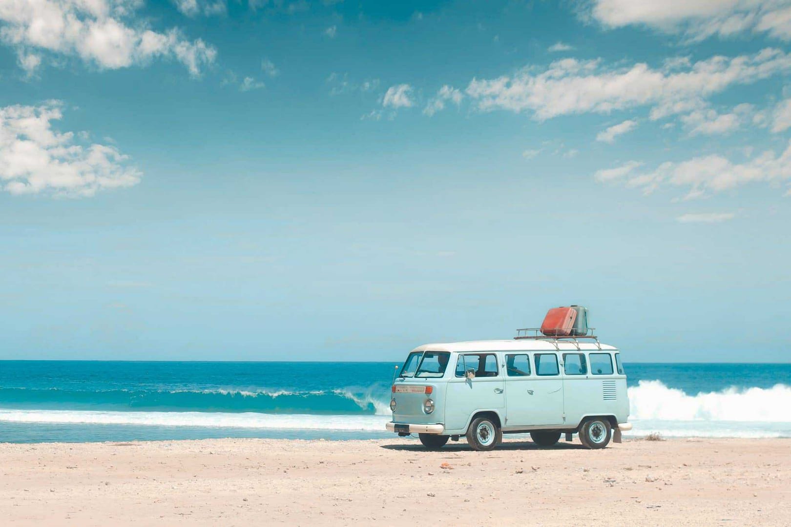 A Volkswagen campervan parked on the beach near the ocean in Australia.
