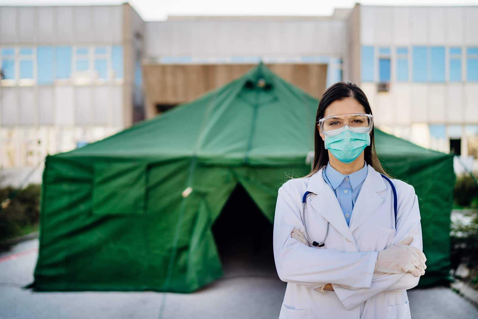 In Queenstown, a woman wearing a medical mask stands in front of a tent.