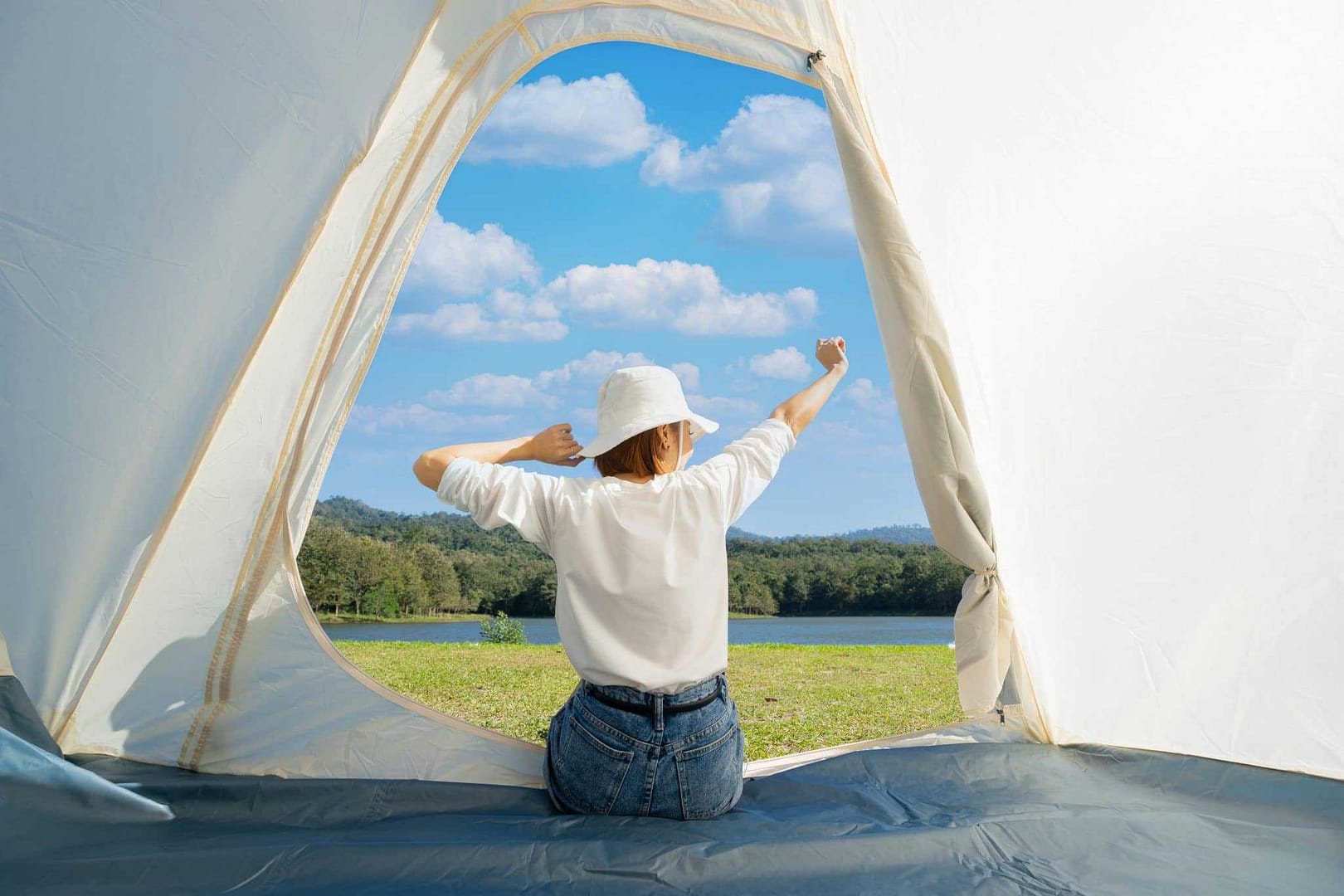 A Chinese woman sitting in a glamping tent, looking out the window.