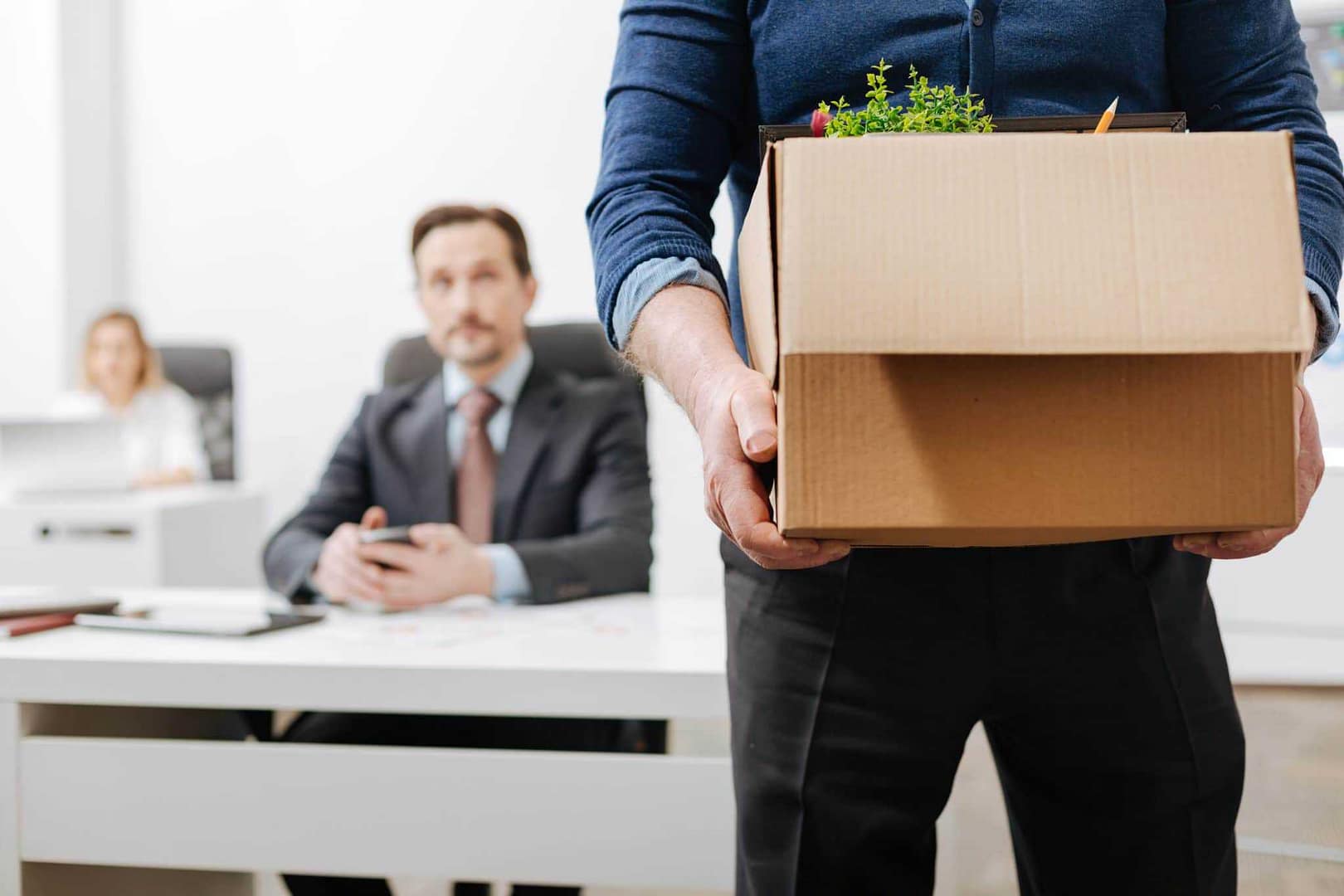 An employee holding a cardboard box while quitting their office job to work remotely.