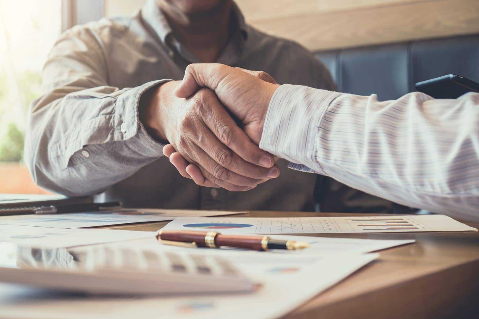 Two men shaking hands at a table in New Zealand.