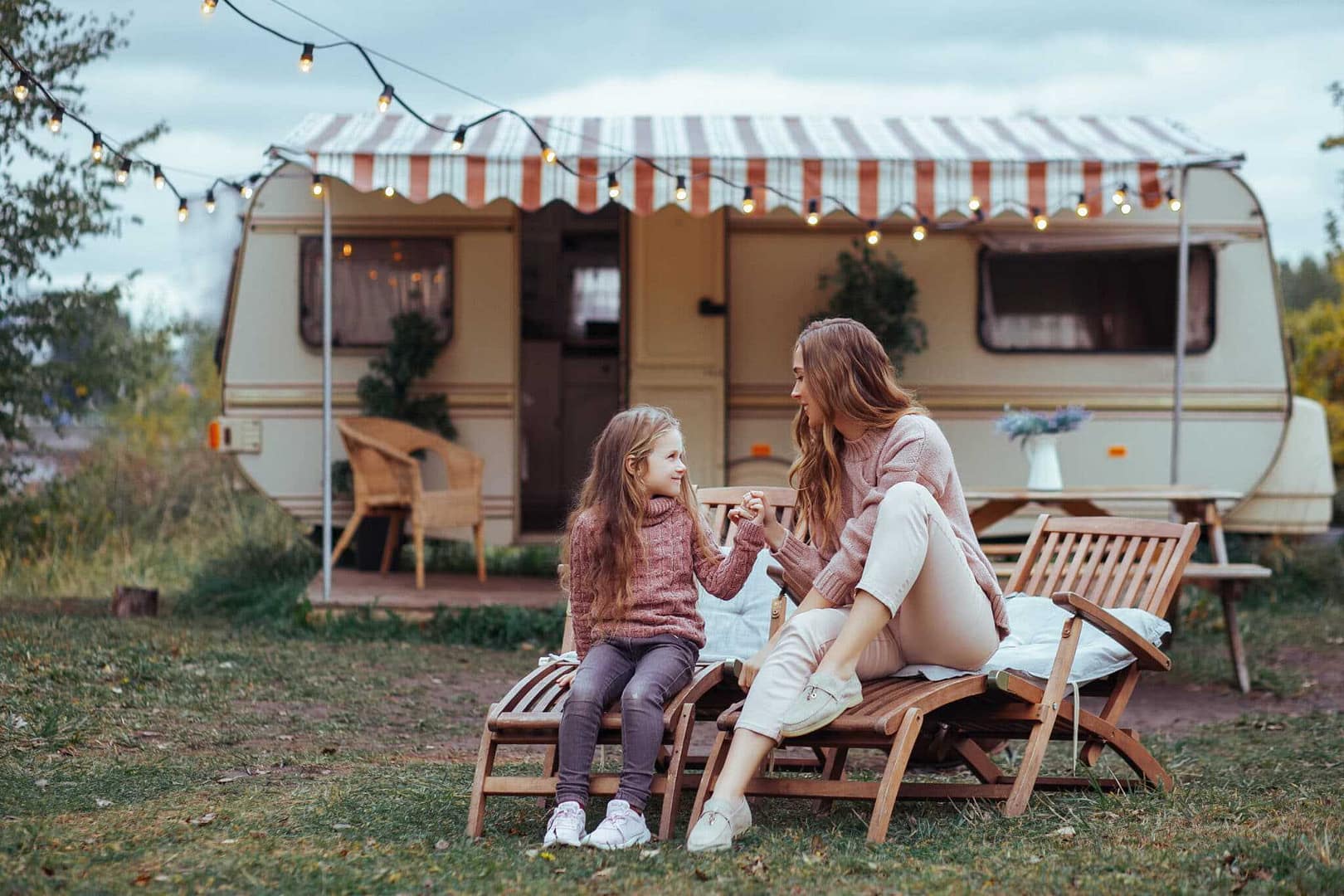 A family sitting in front of a camper trailer at the Moeraki Boulders Holiday Camp.
