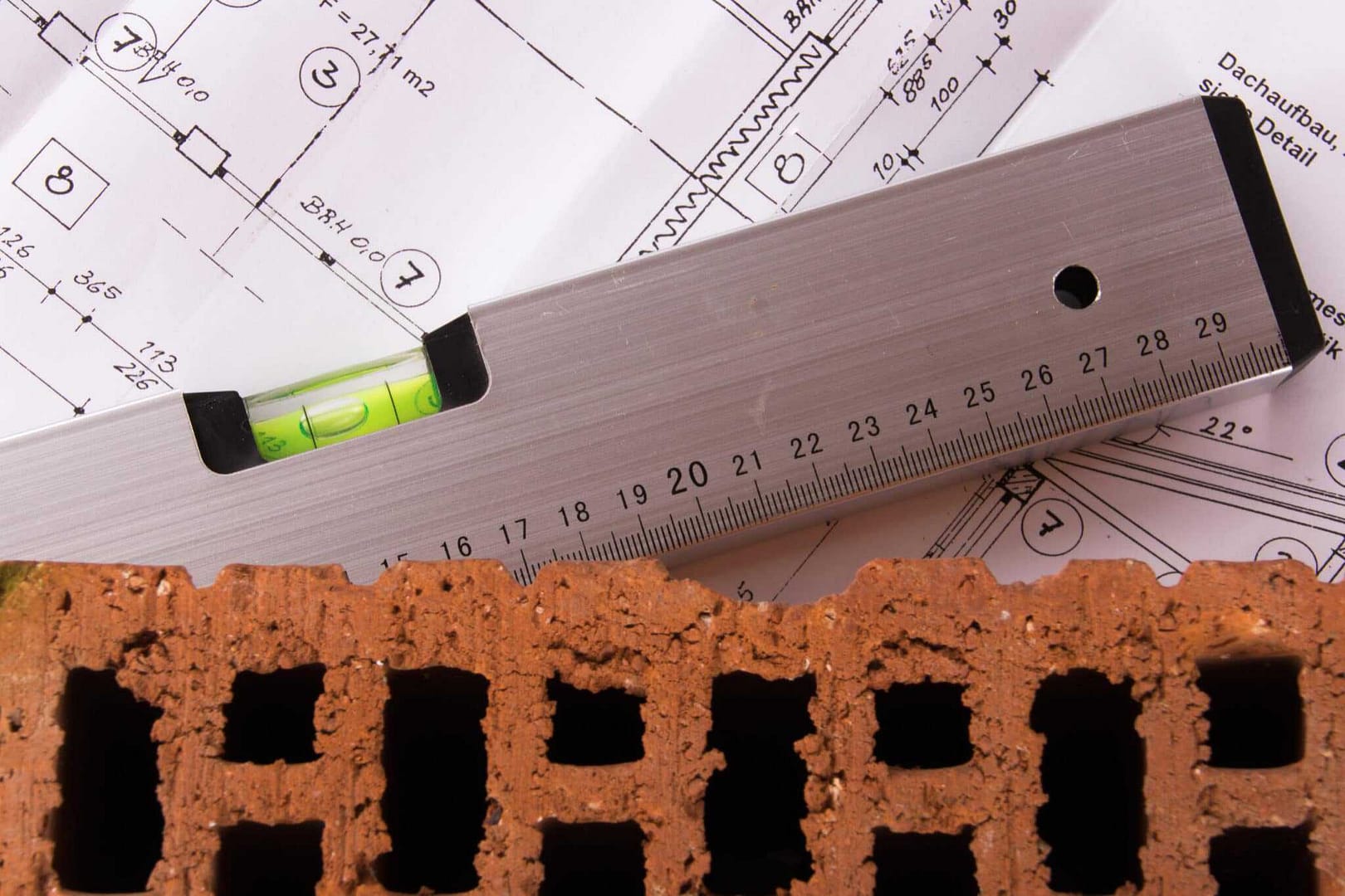 A brick wall with a ruler and blueprints.