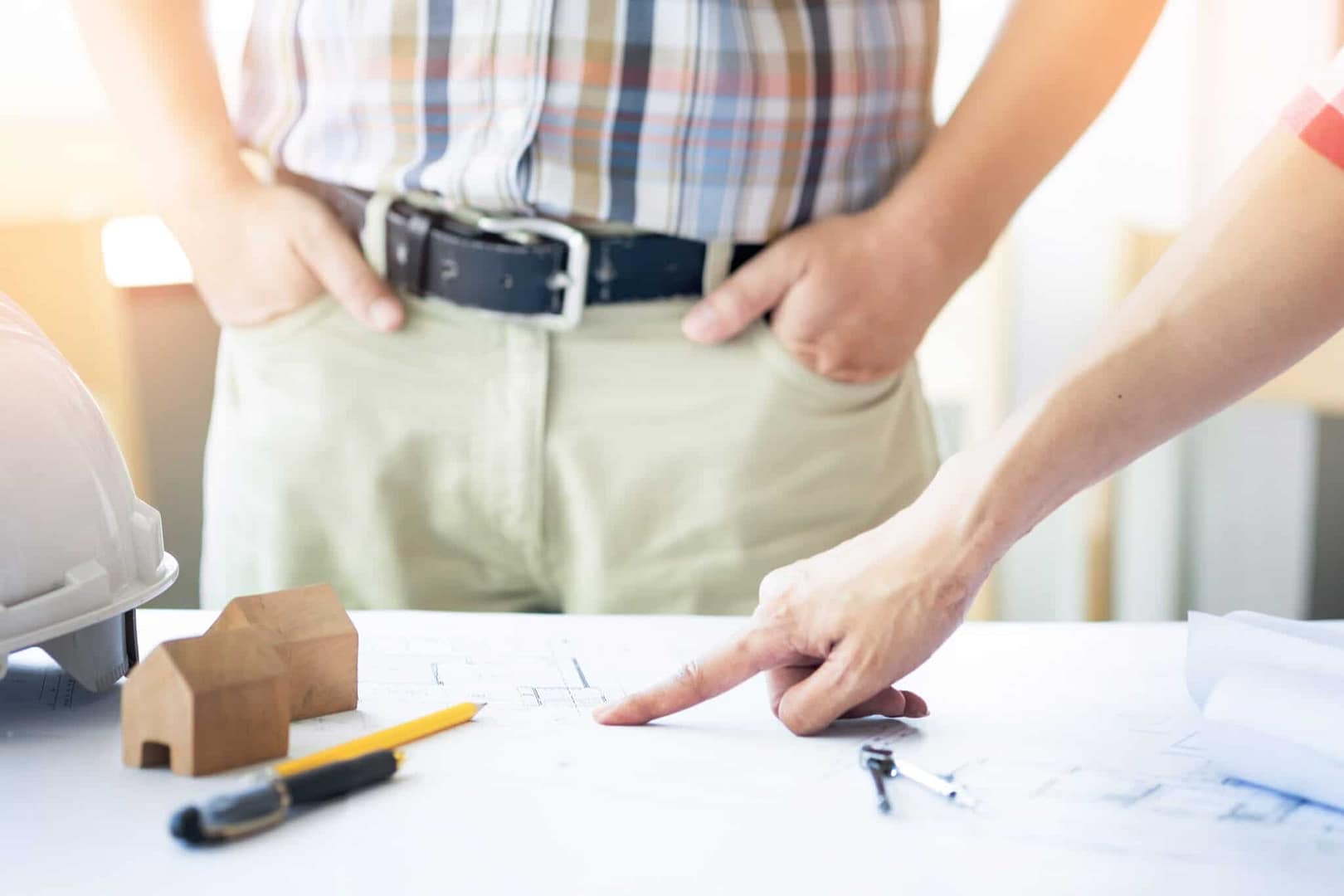 A man and a woman, involved in construction, deeply focused as they examine blueprints.