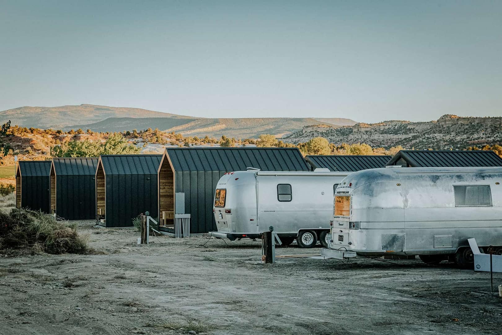 A group of airstream trailers parked in a dirt lot at a glamping site in Utah.