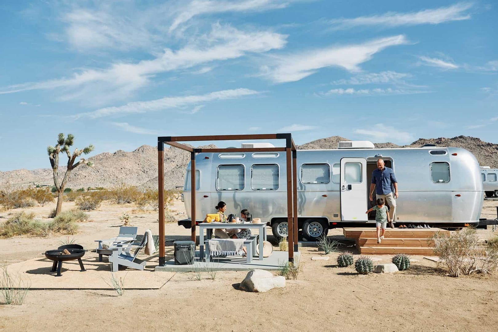 An Autocamp airstream parked in the desert with a table and chairs, offering unique travel experiences.