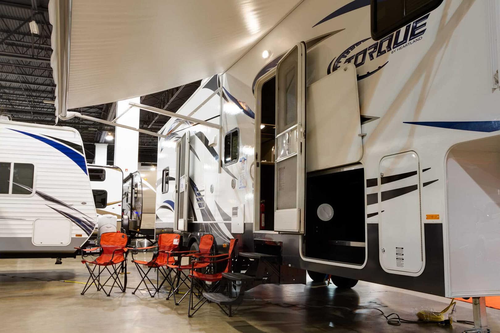 Two rvs in a showroom with chairs and tables.