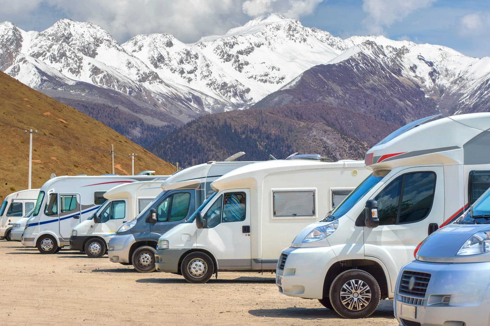 A row of RVs parked in front of snowy mountains, in compliance with the Bonnechere Valley RV Bylaw.