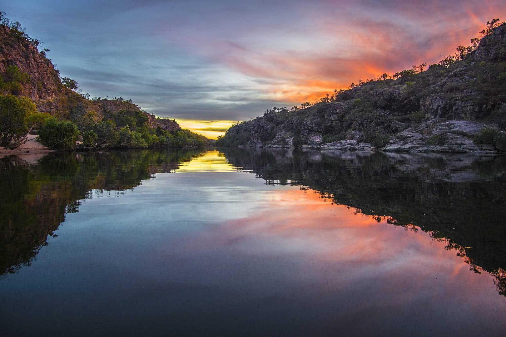 A sunset is reflected in the water of a river at Northern Territory Parks.