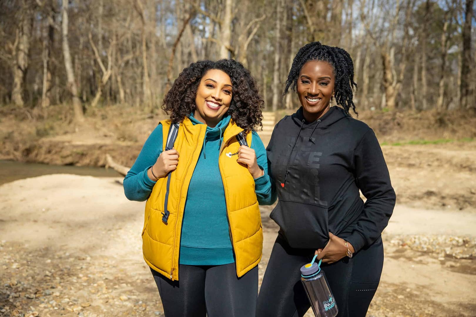 Two women standing next to each other in the woods, participating in the Women's Mental Health Initiative.