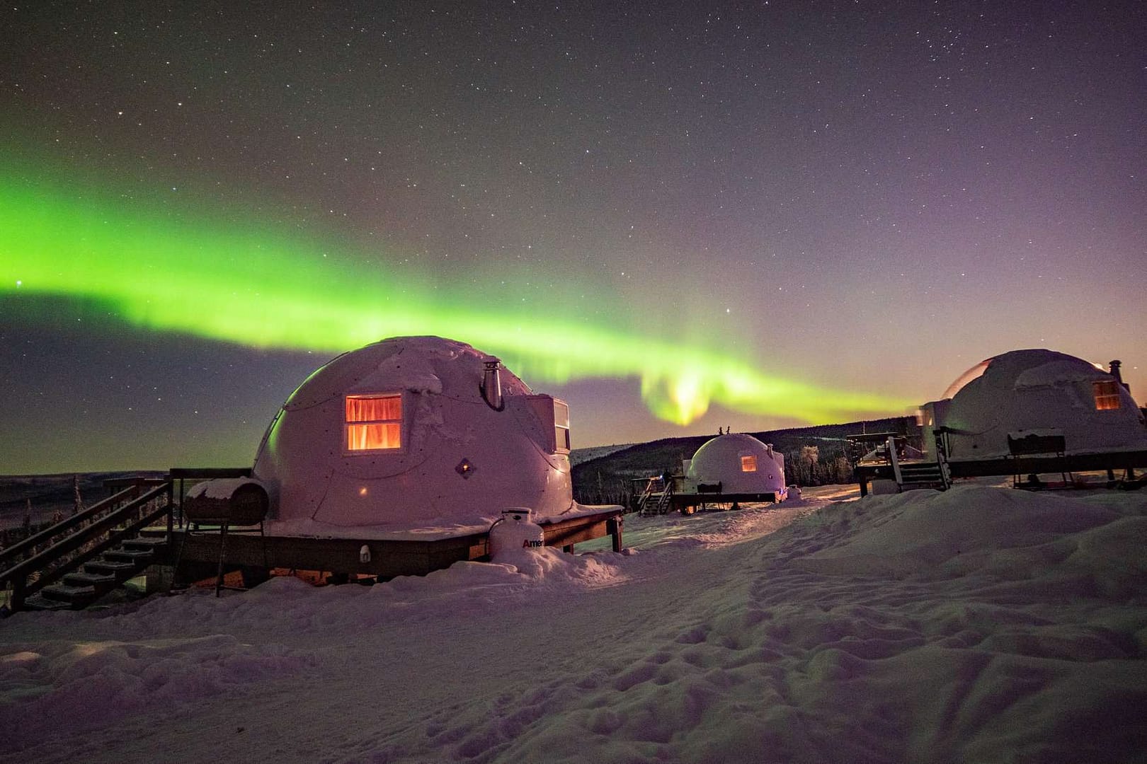 A cluster of luxurious igloo huts nestled under the awe-inspiring aurora borealis.