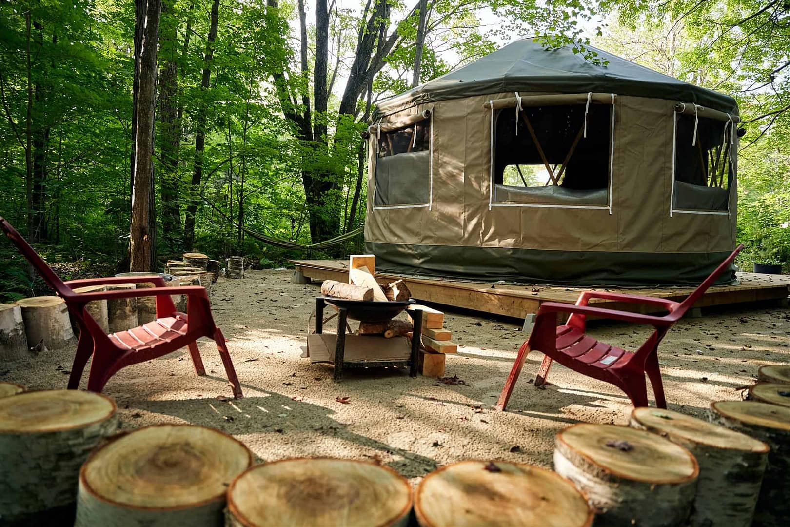 A glamping site with a yurt, chairs, and a fire pit nestled in the woods just outside of downtown Ottawa.