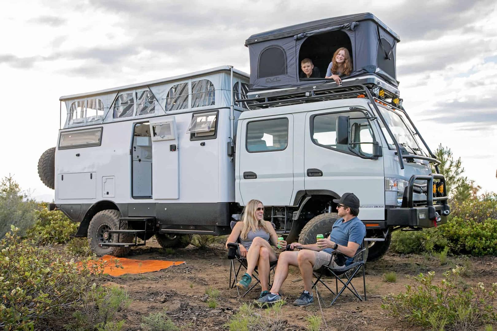 A group of people camping on top of a camper truck.