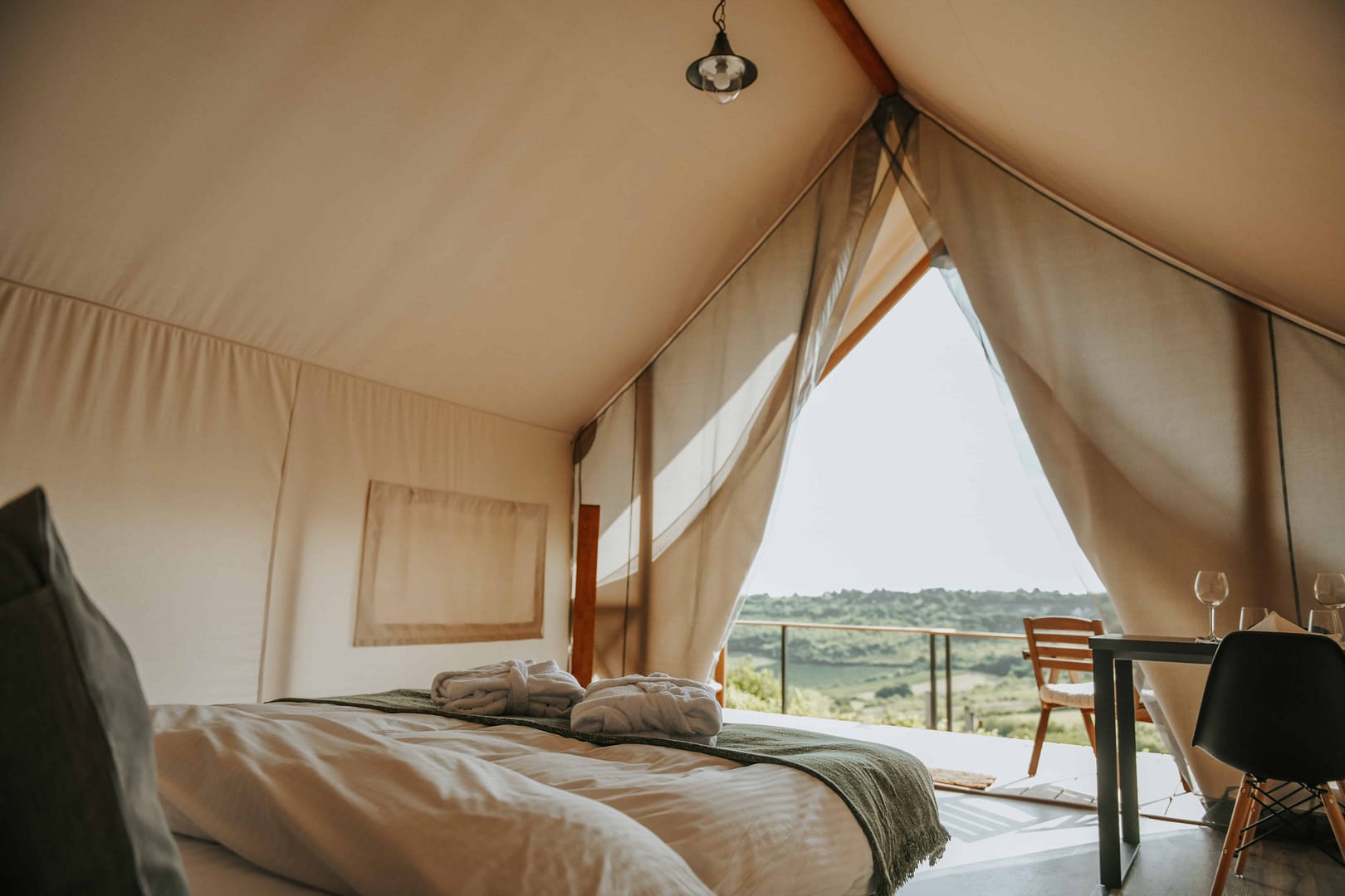 A bed in a tent with a scenic view of the mountains.
