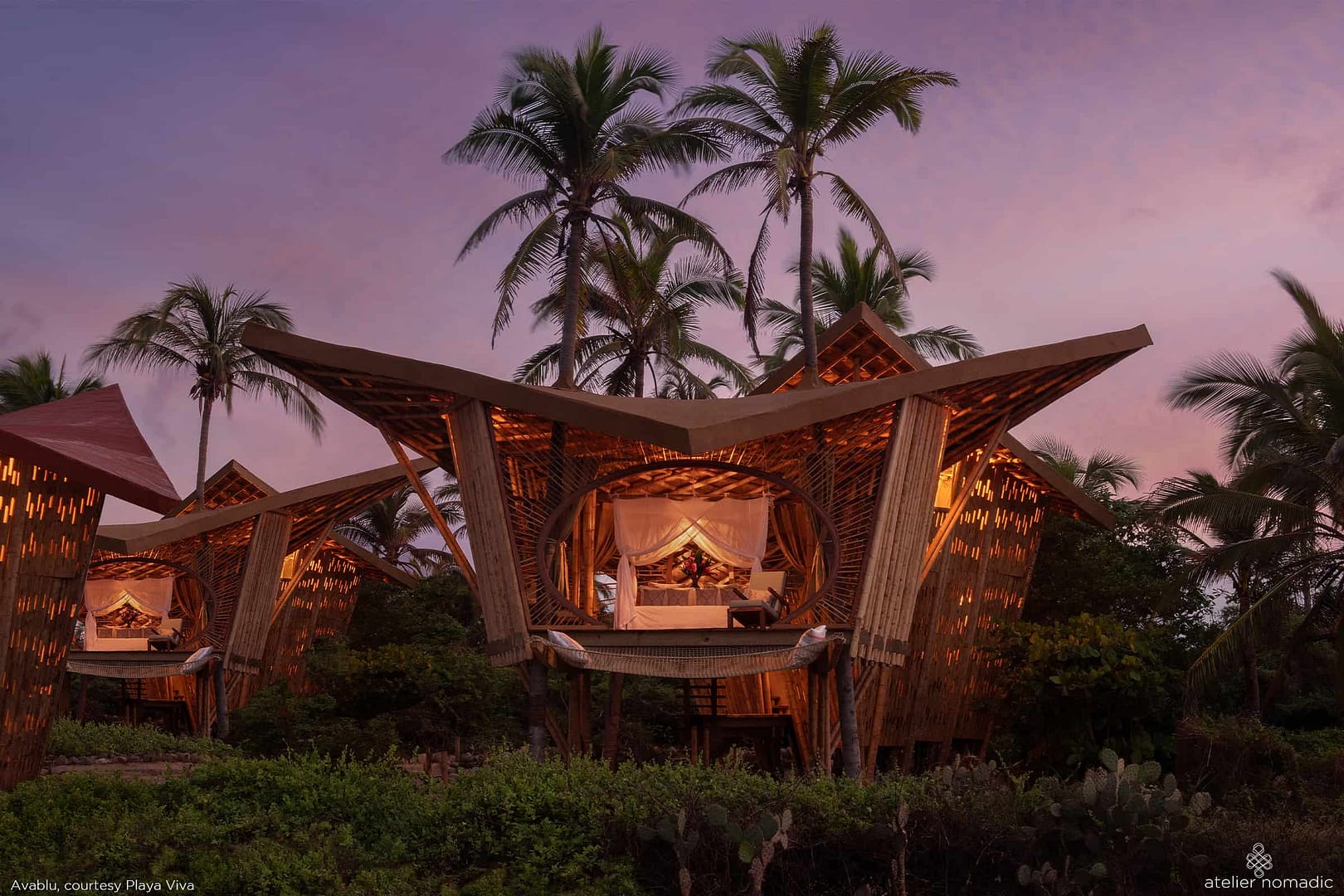 Two Nomadic Resorts tree houses in the middle of the jungle at dusk, offering a unique hospitality experience.