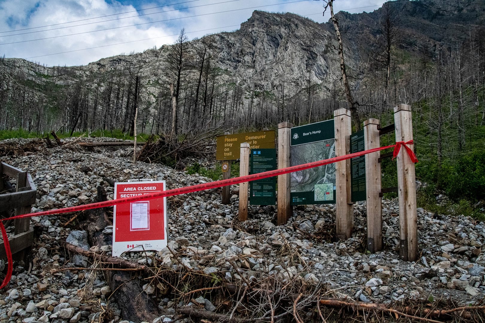 A sign with red tape on it in front of Waterton Lakes National Park amidst closure due to flooding.