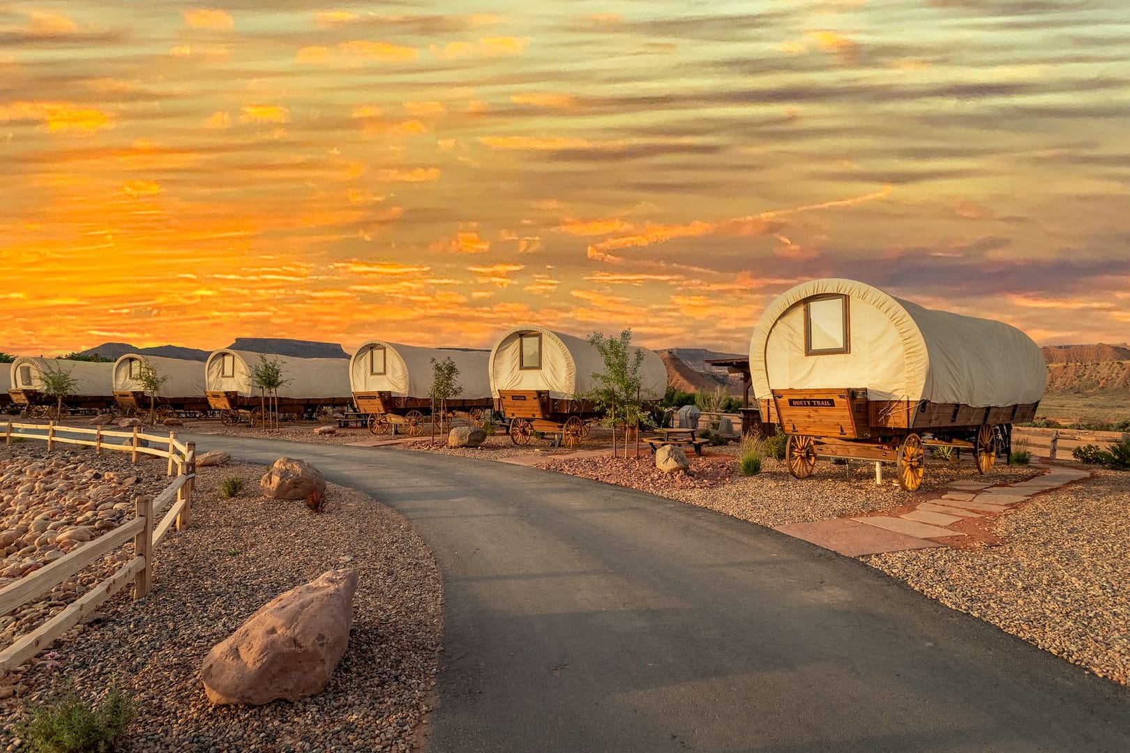 A group of Covered Wagons from PlainsCraft lined up on a road at sunset.