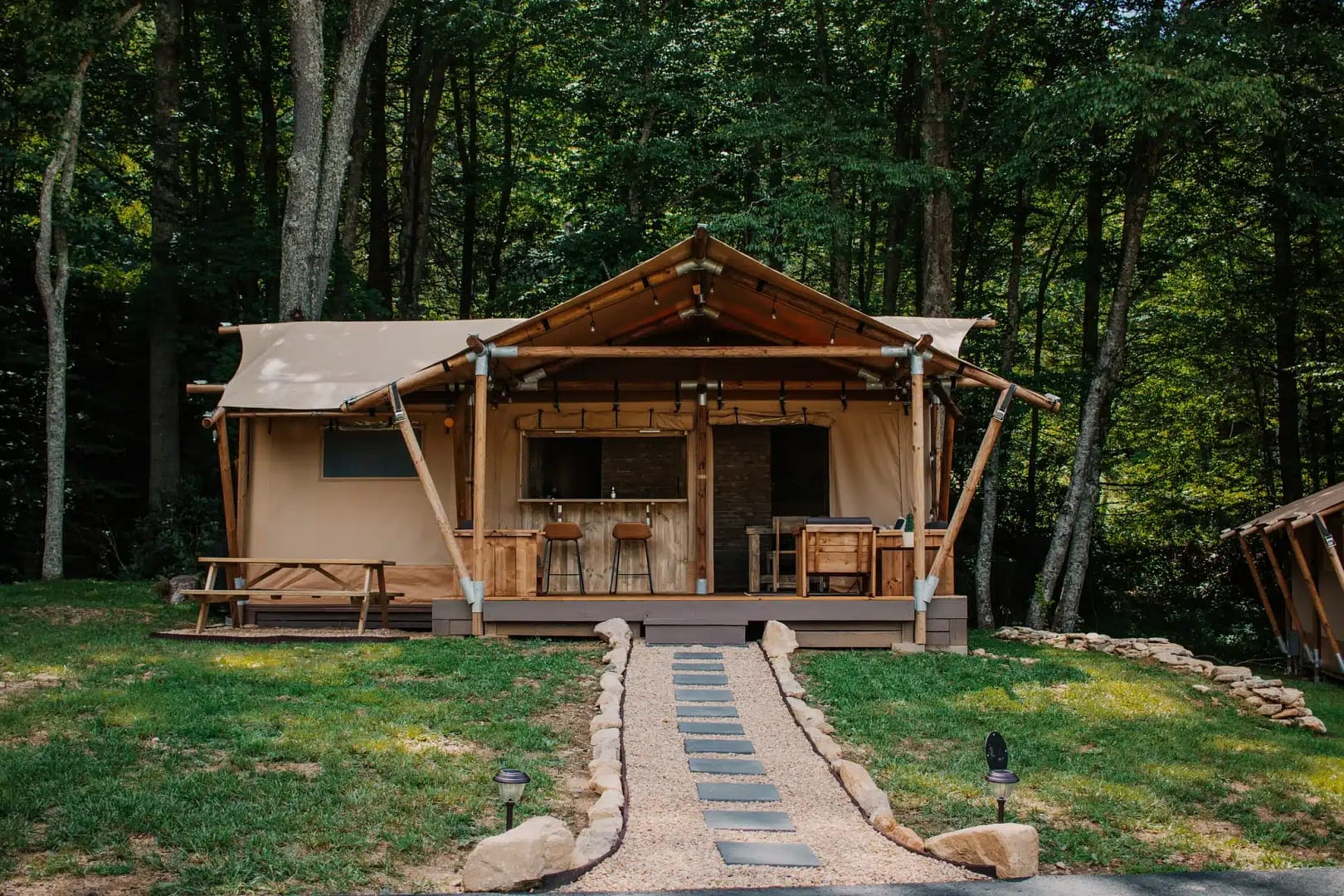 A tan tent sitting in the woods, designed with glamping retro story in mind.