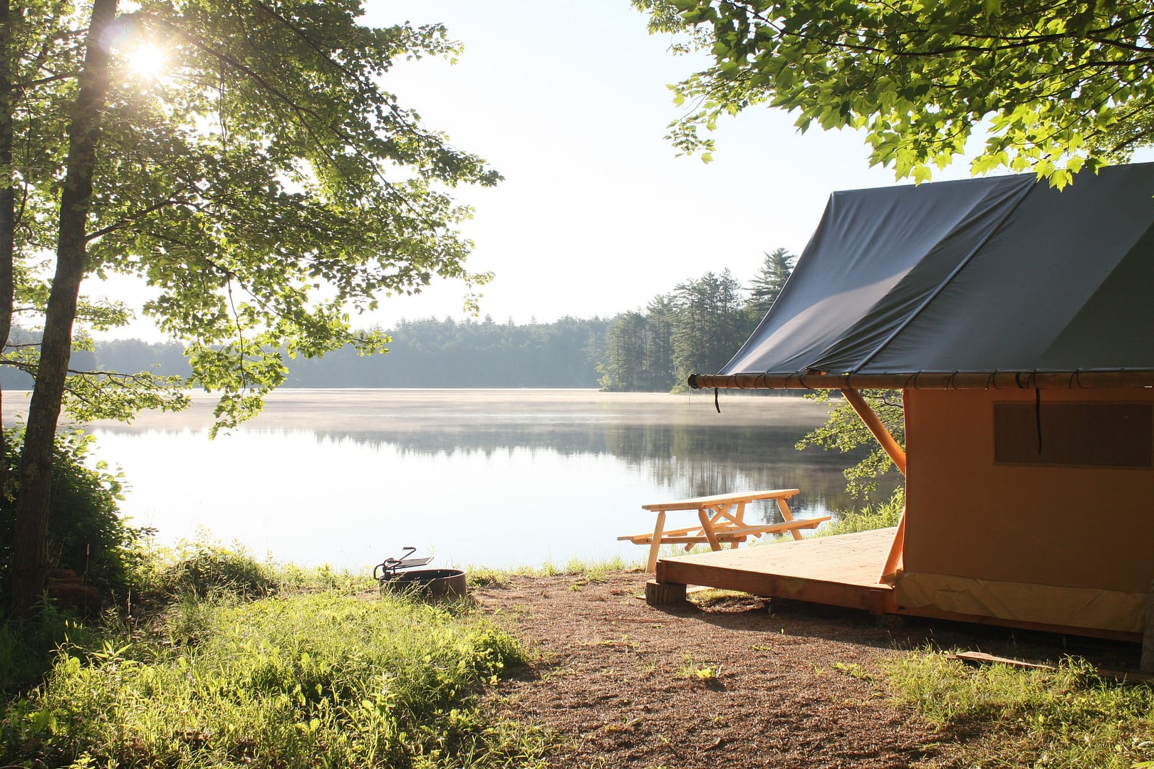 A Huttopia tent next to a lake.