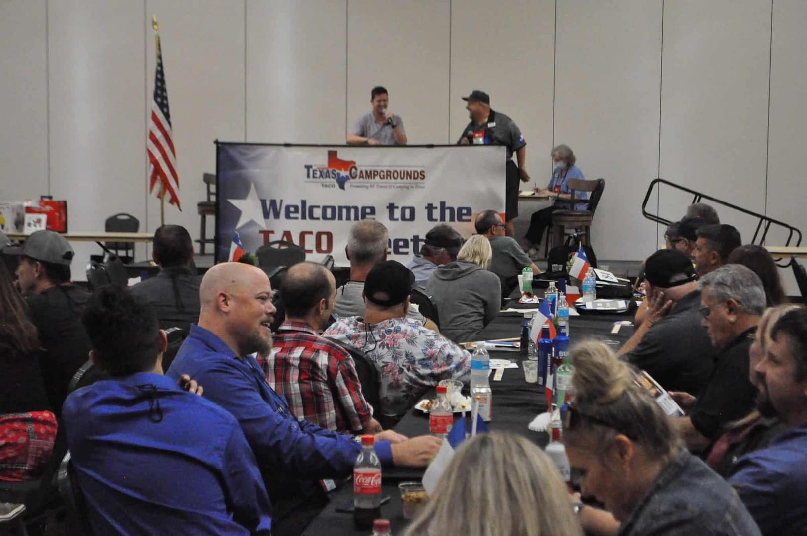 An award-winning group of people sitting at tables at a convention.