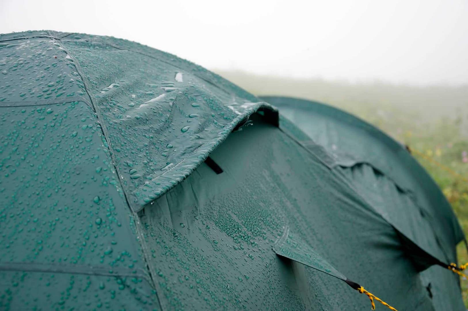 Australian Campers set up a green tent on a grassy field.