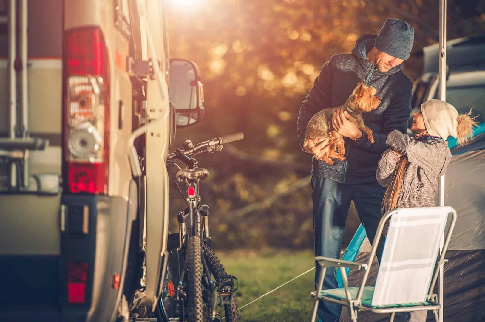 A family of RV owners is camping in front of their travel trailer.