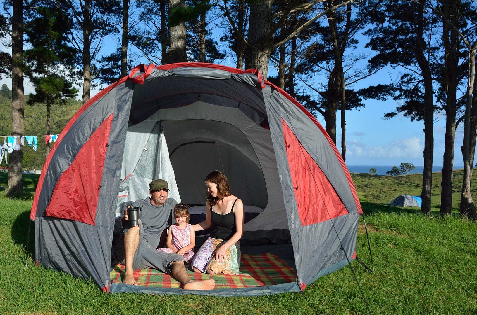 A family is enjoying responsible outdoor recreation in New Zealand while sitting in a tent, embracing the conservation of nature.