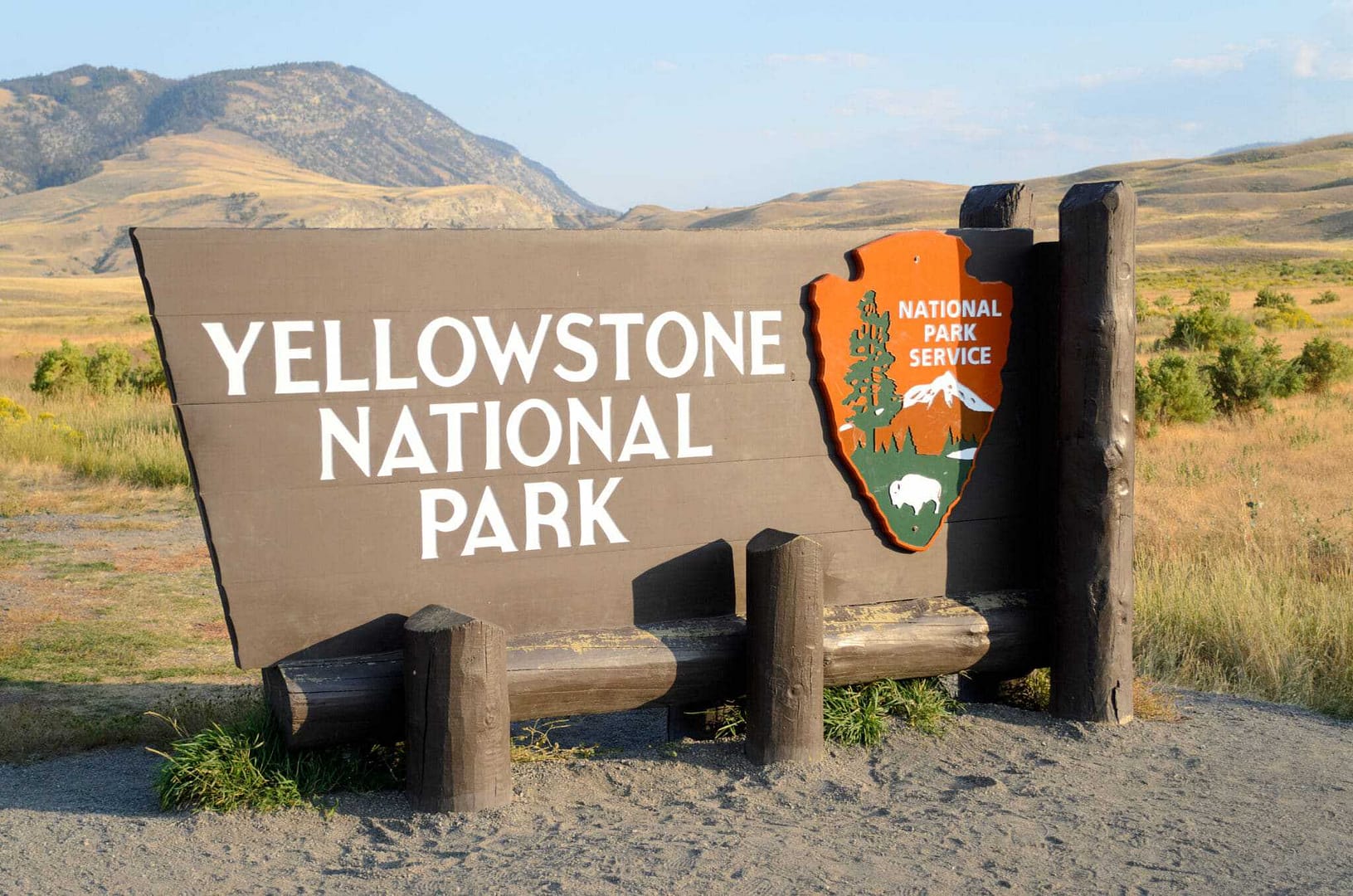 A yellowstone national park sign in front of a mountain.