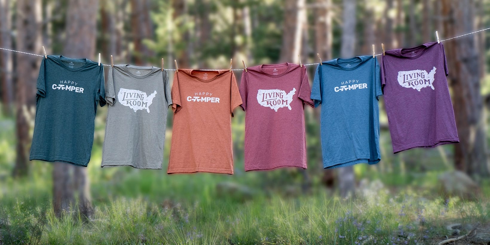 Four t-shirts hanging on a clothesline in the woods at CampLife.