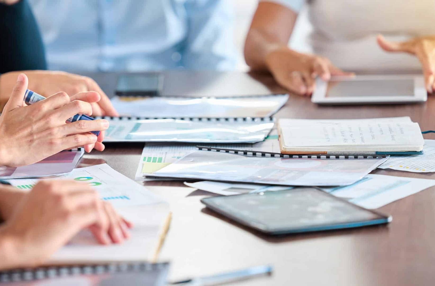 Professionals discussing odor concerns with documents and digital devices on a conference table, hands and papers in focus.