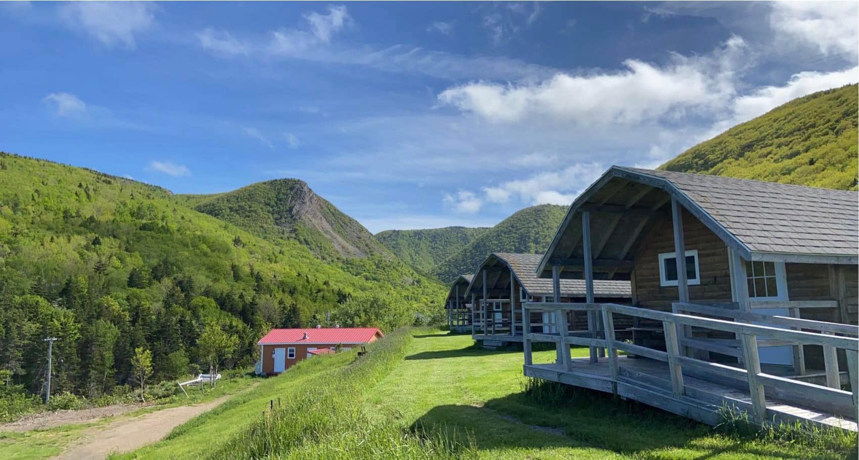 Description: Cabins on a hillside next to a mountain at Cape Breton's Meat Cove Campground.