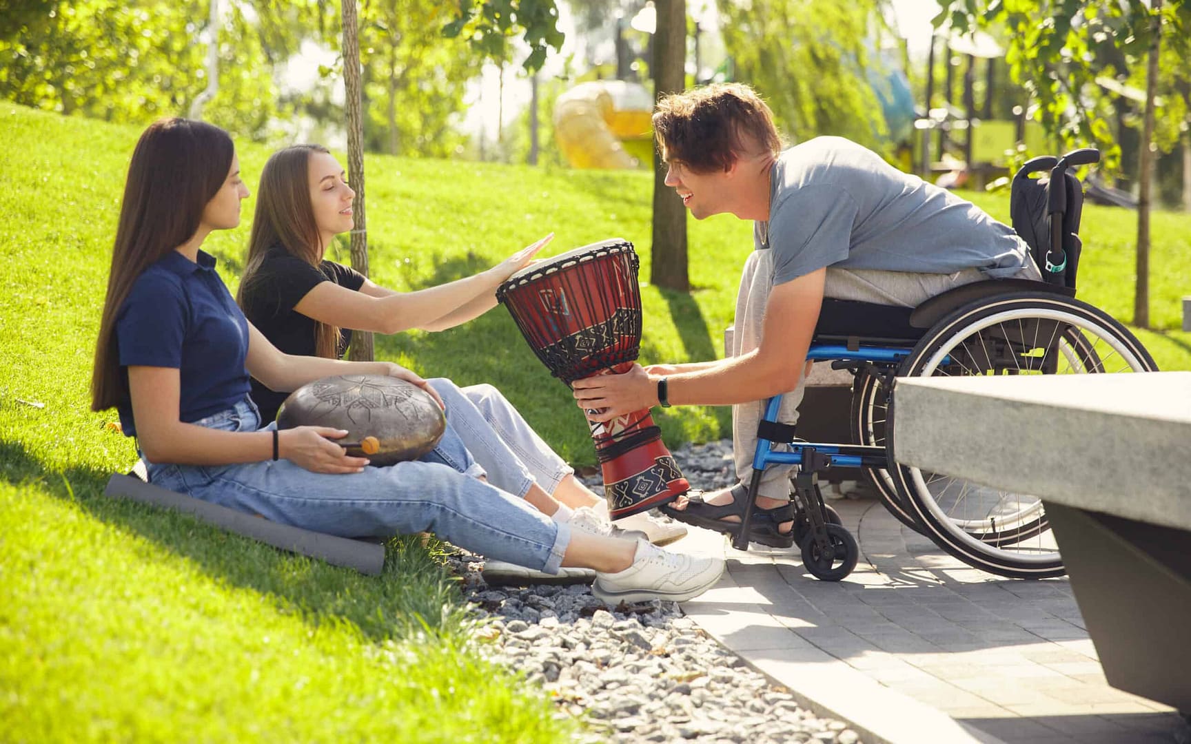 A group of people in a wheelchair playing a drum in an accessible park.