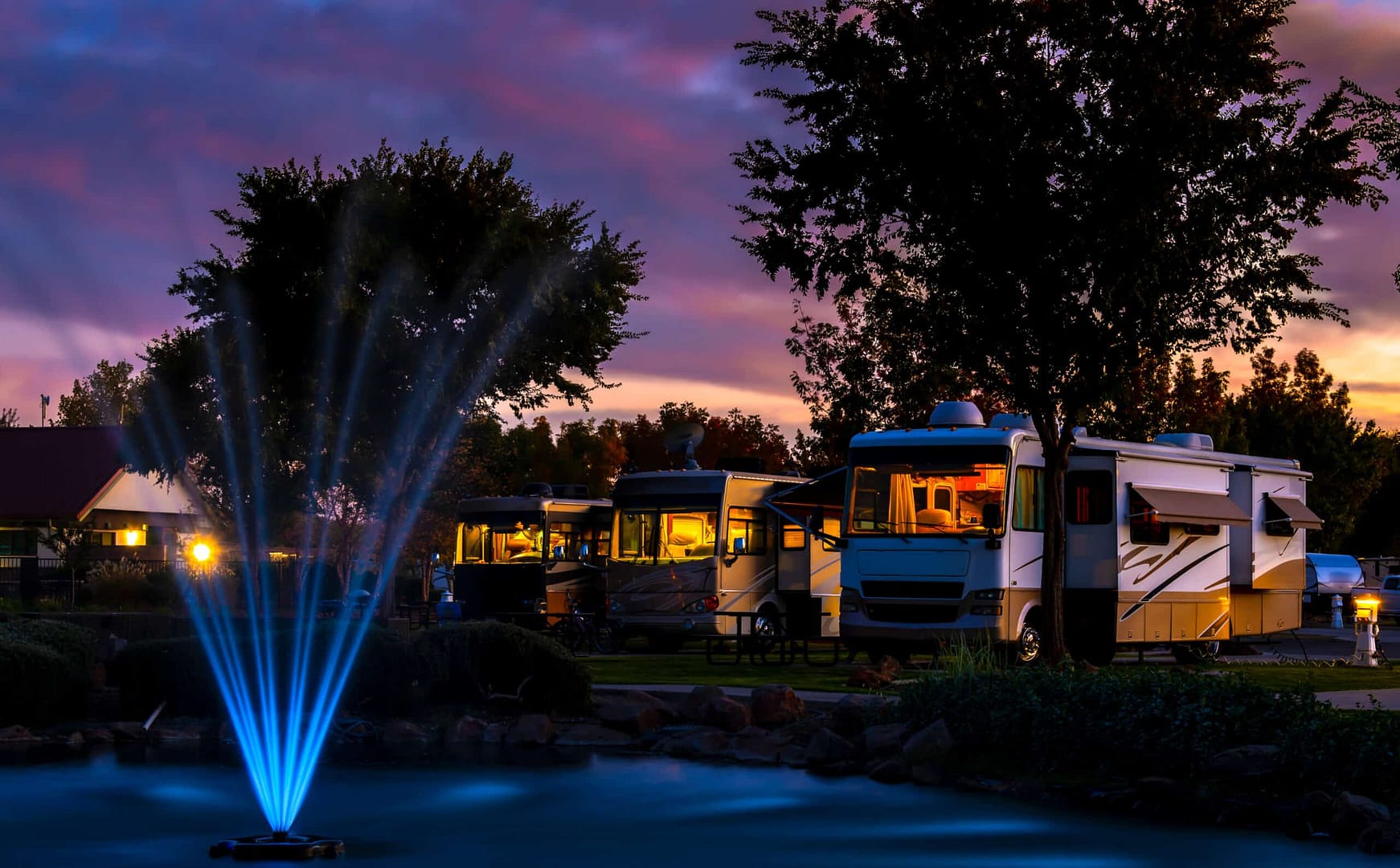 Luxury RV Park at Dusk in Baxter County with fountain and RVs.