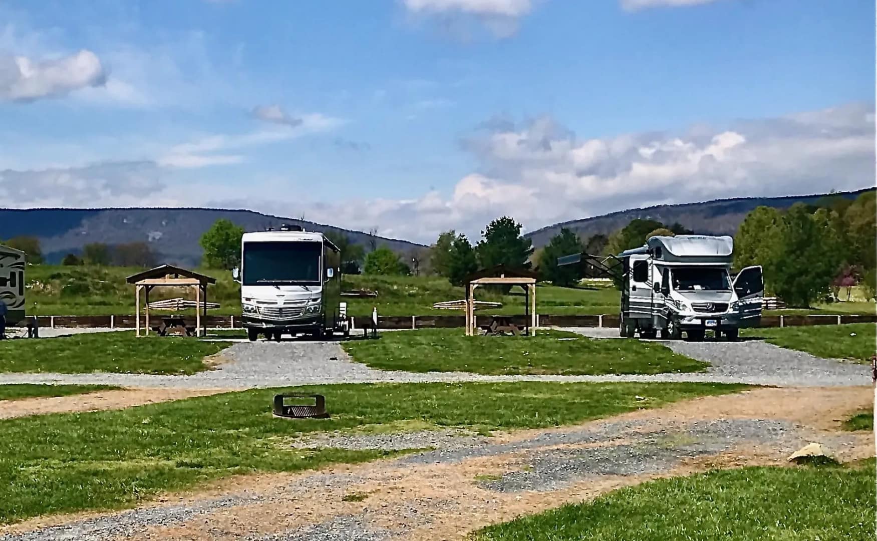 Three RVs parked in the Luray RV Resort, a picturesque campground with majestic mountains in the background, creating a Grand Reveal of nature's beauty.