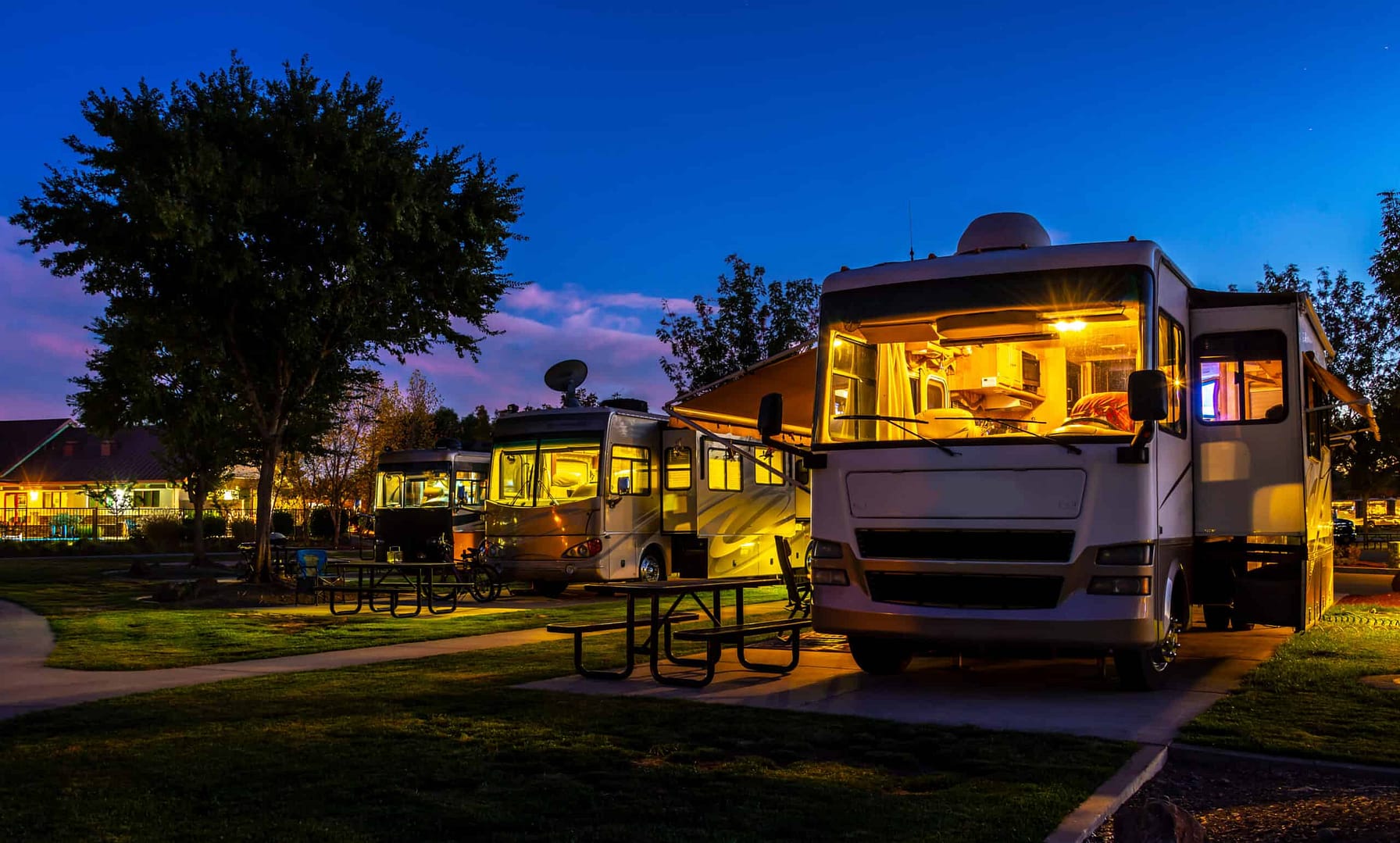 A group of rvs parked in a park at dusk, where recreational area development is taking place.