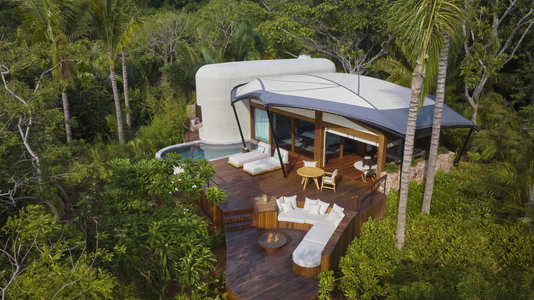 Experience the ultimate luxury accommodations in the Naviva Resort, nestled amidst lush nature. Enjoy an enchanting aerial view of a house surrounded by the mesmerizing jungle.