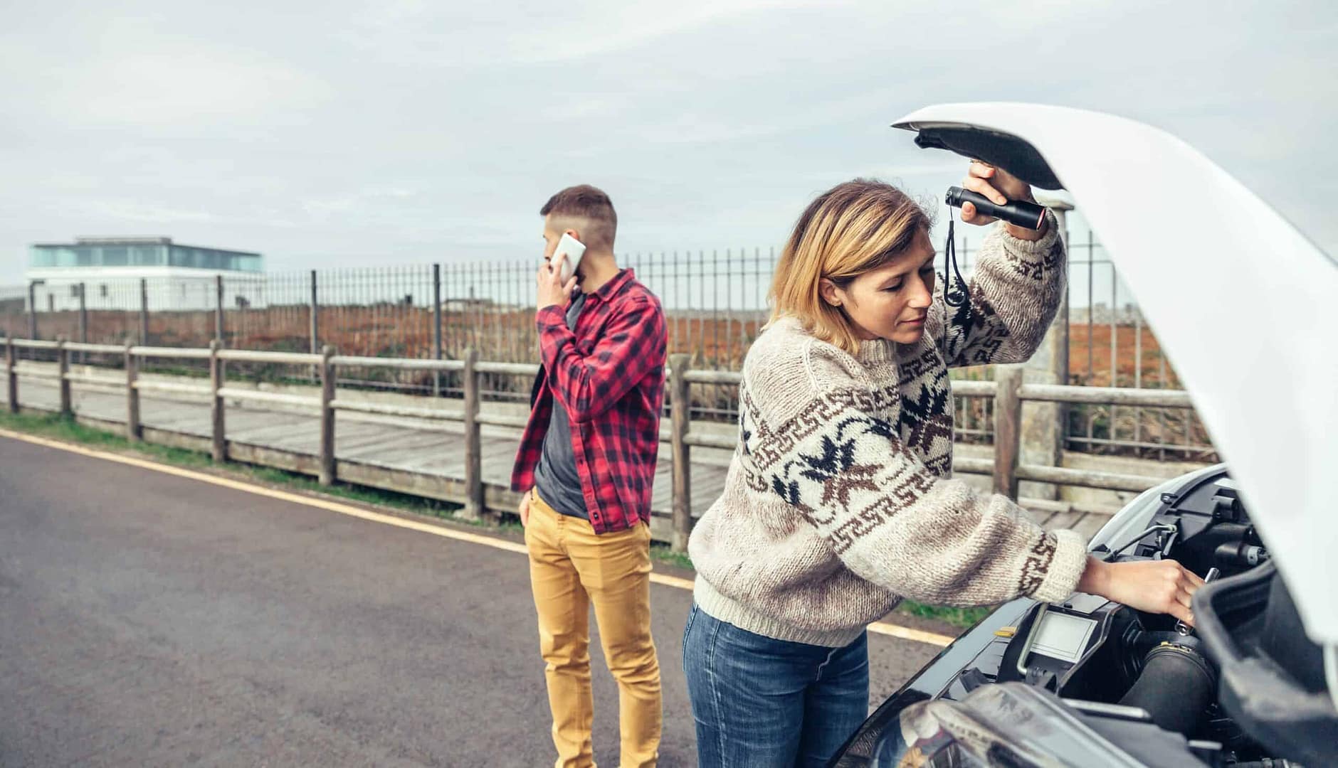 A woman and a man standing next to a car with a broken hood at an RV dealership.
