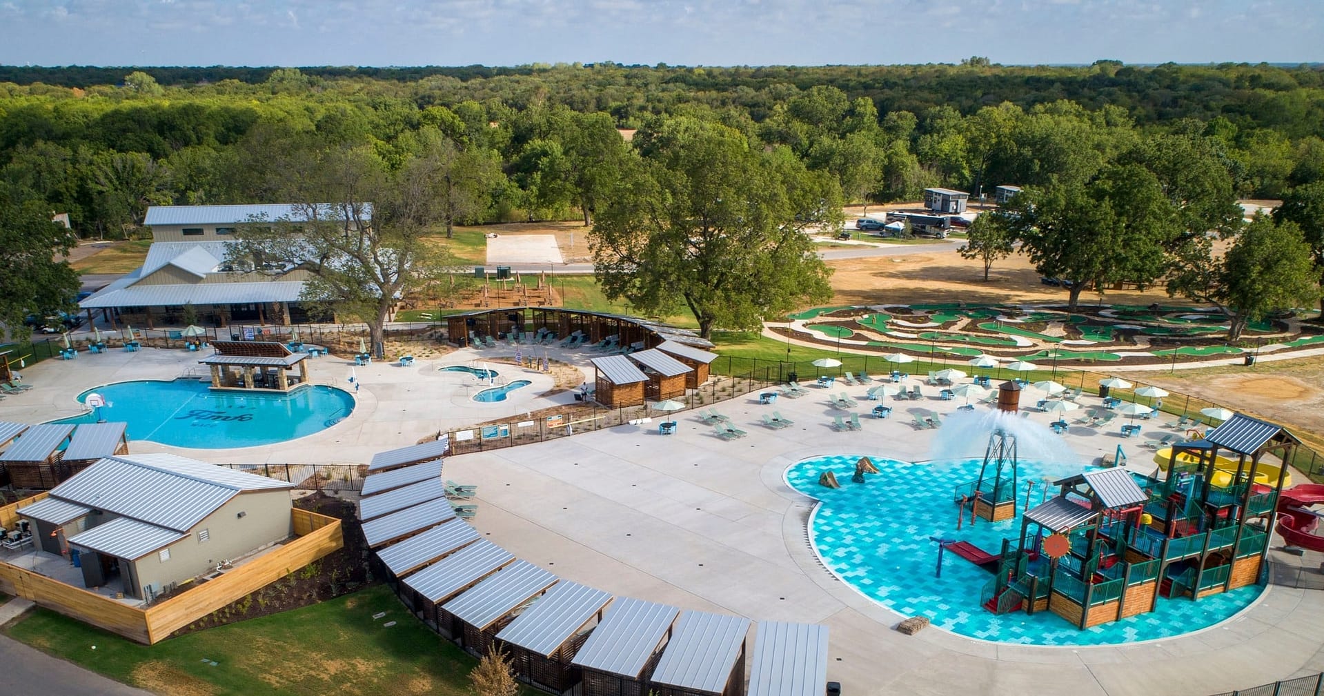 An aerial view of a picturesque outdoor pool and playground nestled in the serene Texas Hill Country.