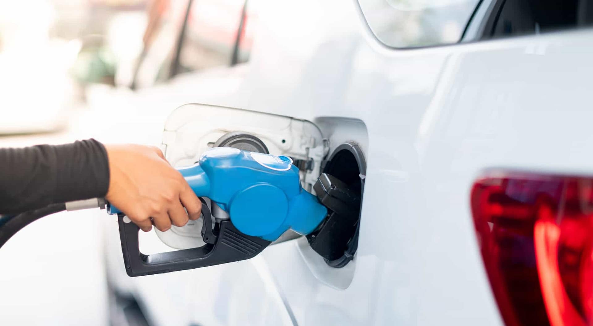 A person filling up a car with fuel while gas prices sink slowly.