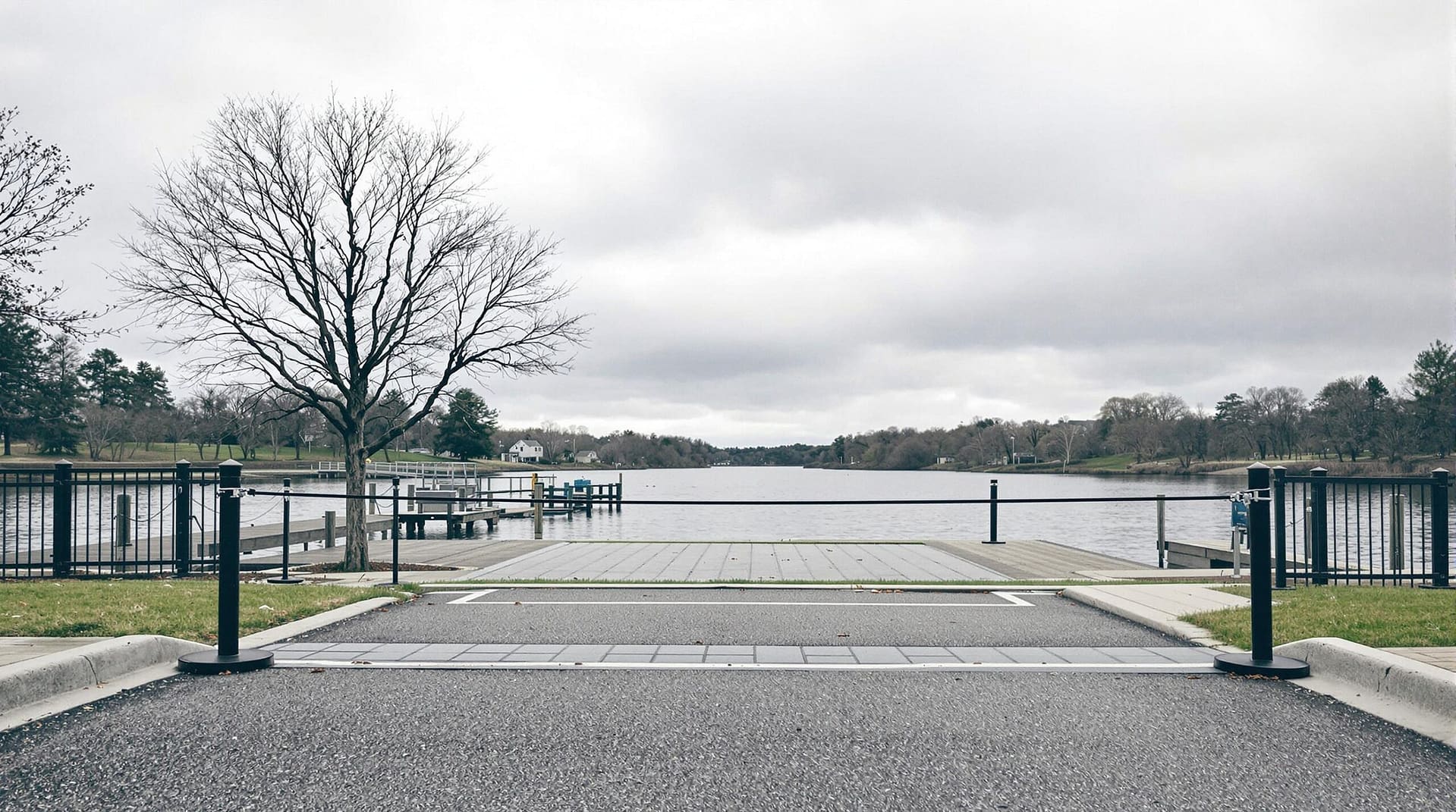 A closed gate at a riverside recreation area on a cloudy day, with soft natural lighting and a neutral background, indicating a temporary closure without any identifiable landmarks or text.