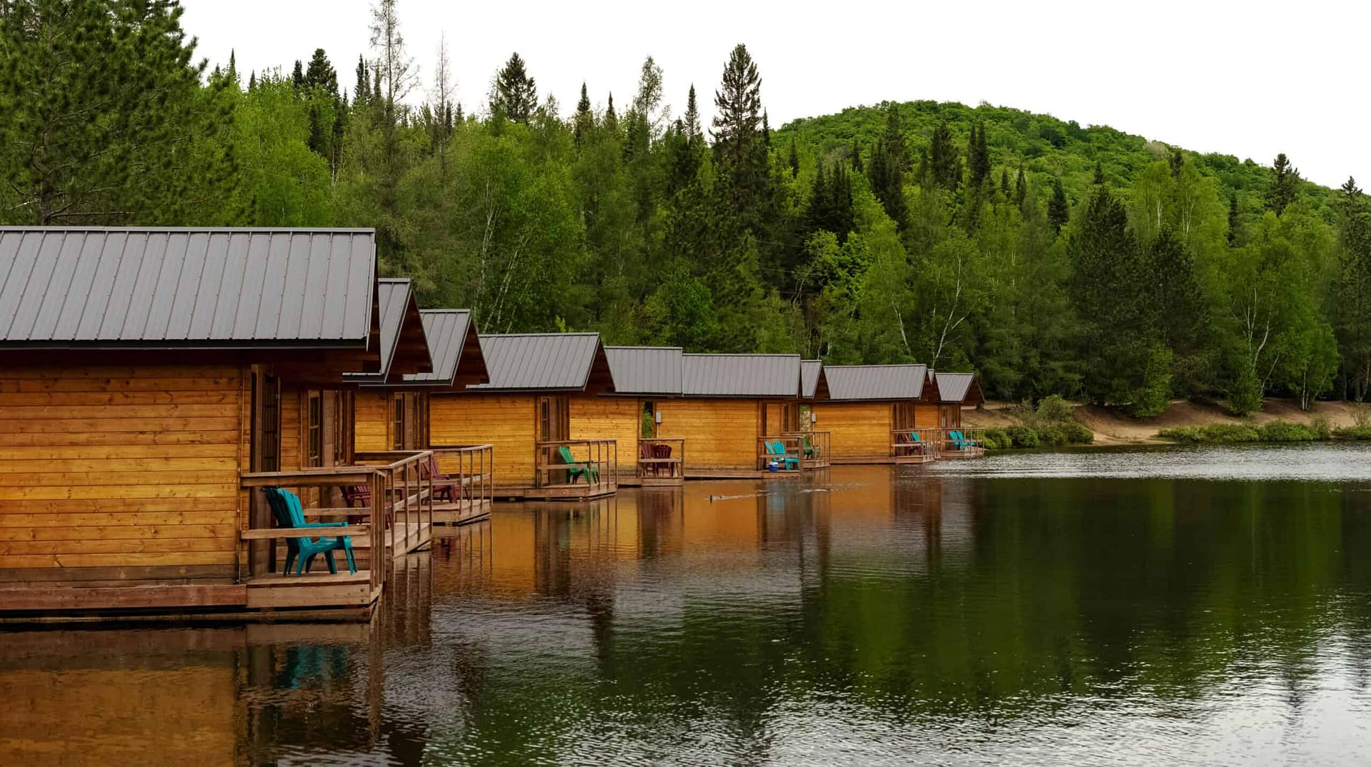 Cabins on a lake surrounded by lush trees, offered by United Park Brokers.