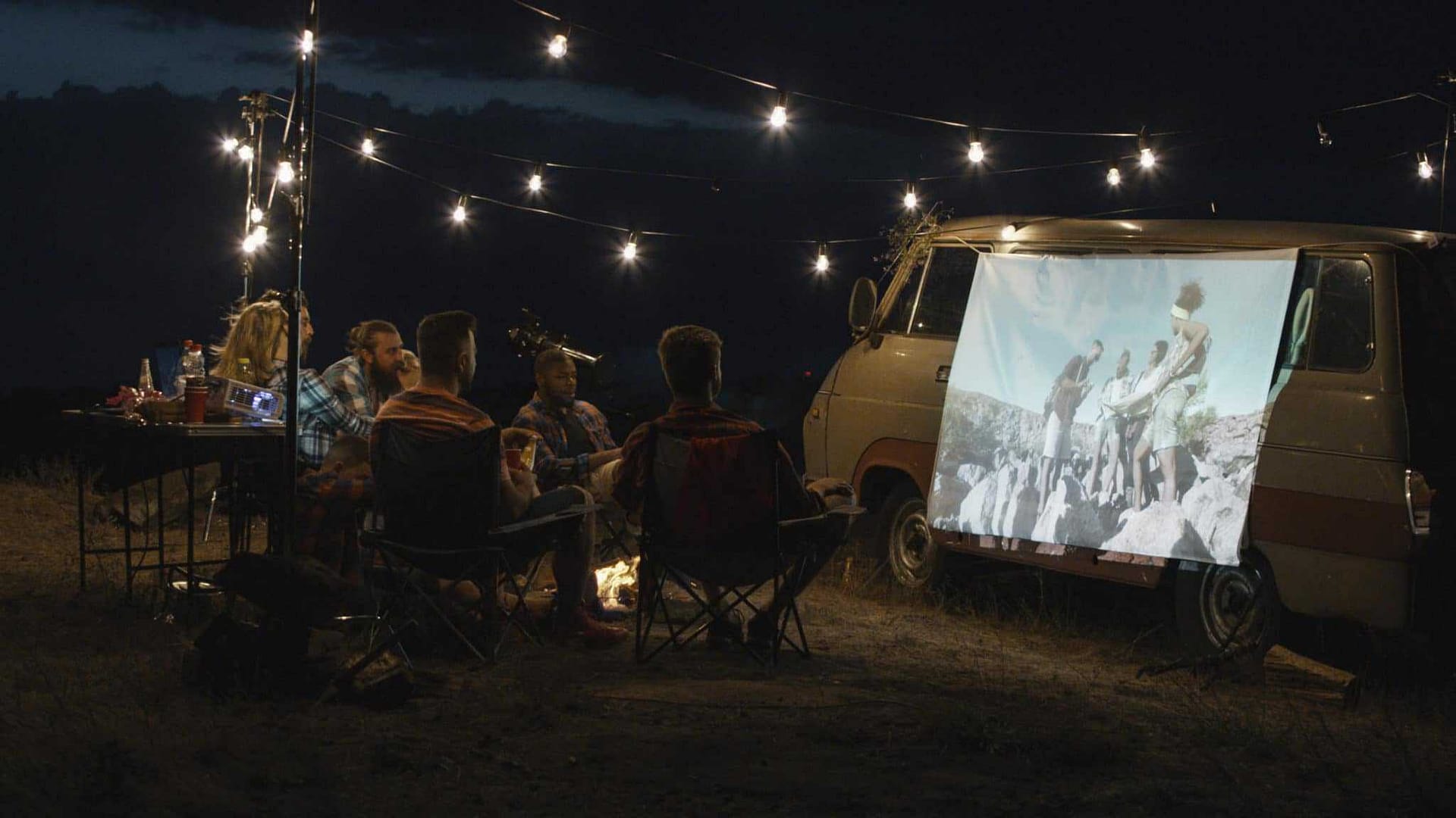 A group of people camping around a camper van at night in Michigan Park.