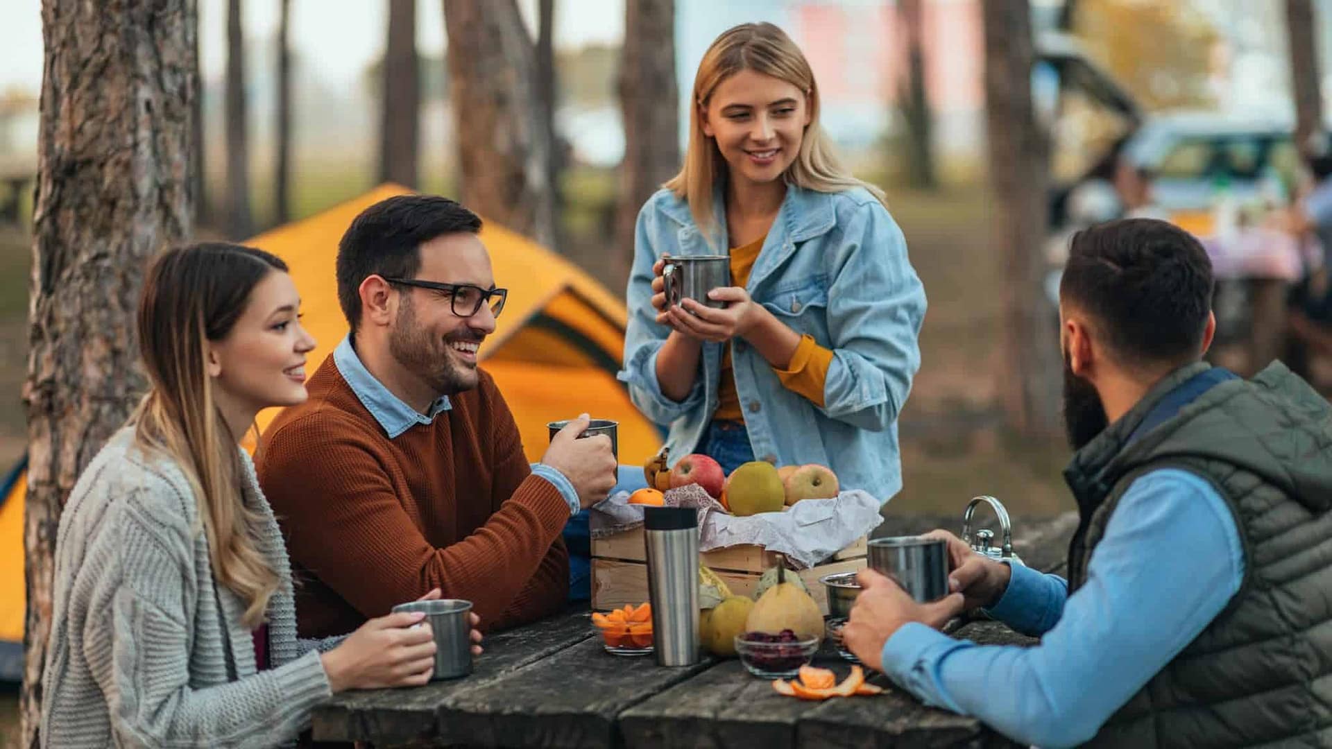 A group of friends sitting around a picnic table in the campground.